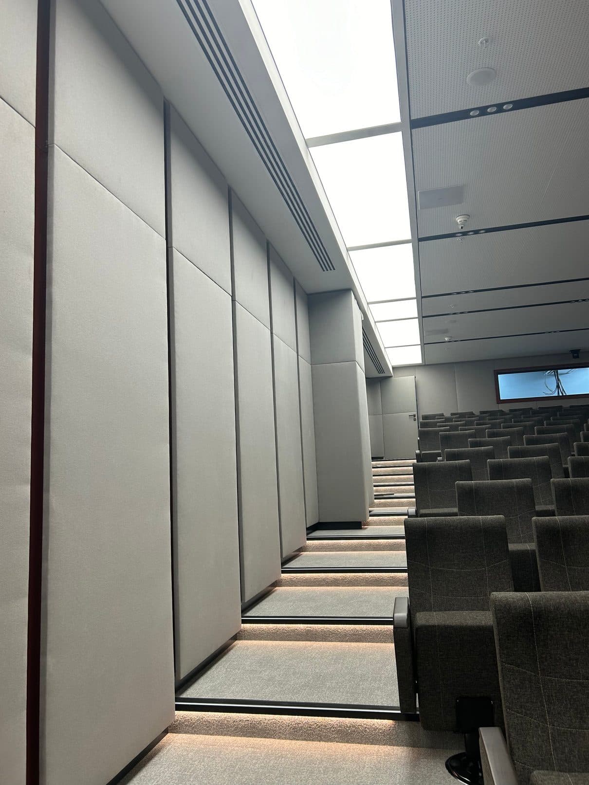 Konferans salonu yan koridorunda panel duvarlar ve basamak aydınlatması